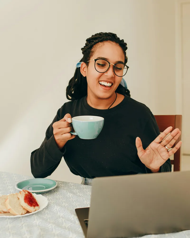 Smiling business owner with a cup of tea on a friendly video call