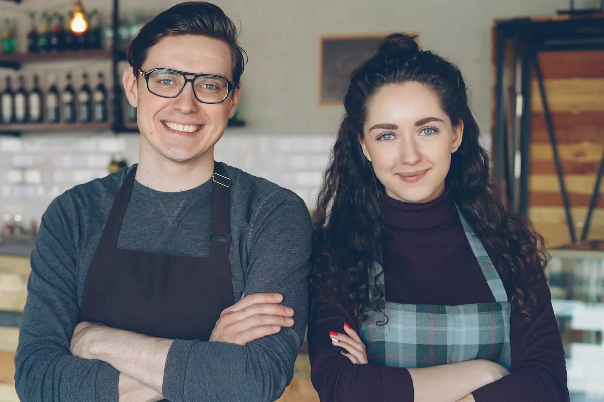 Two smiling café owners standing in their shop