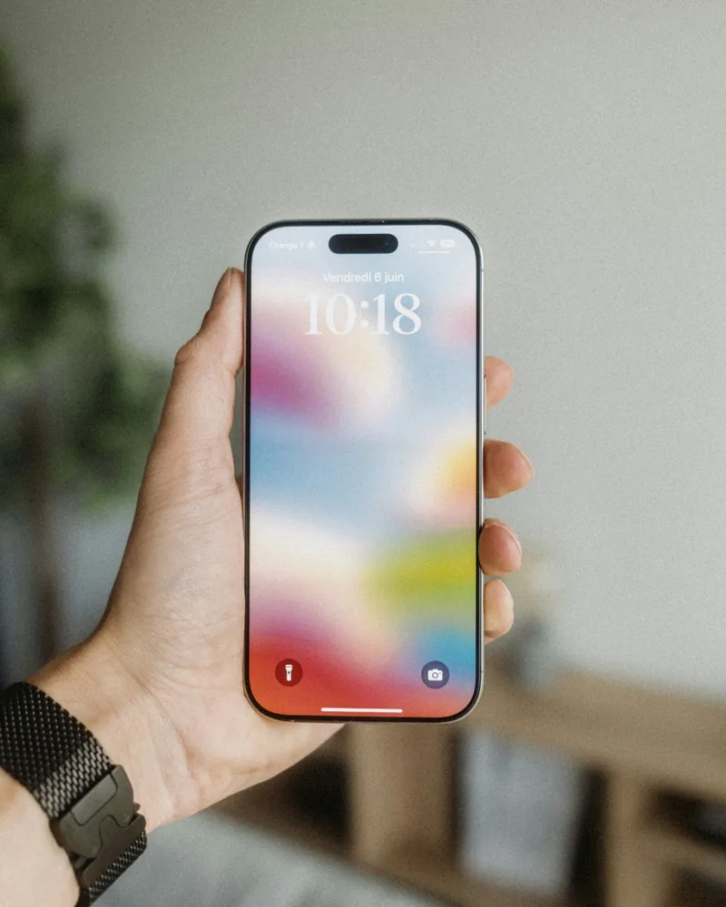 Hand holding a smartphone with a colourful lock screen